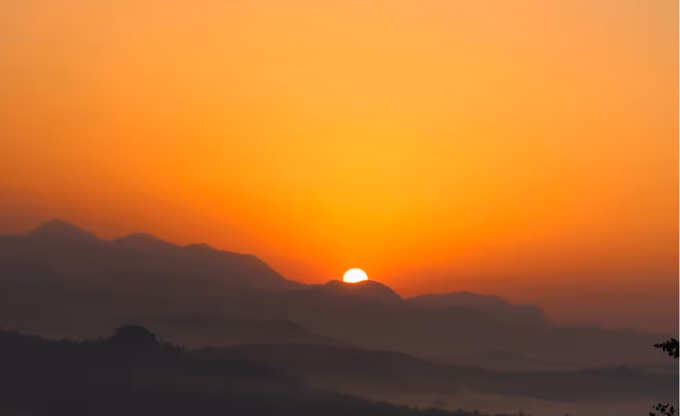 Sunset over mountain silhouettes with vibrant orange and yellow sky